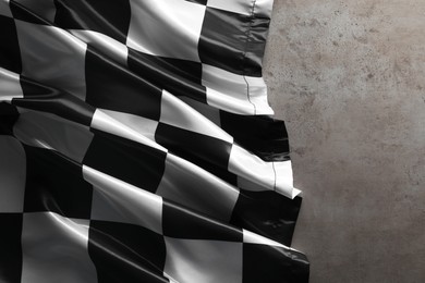 Photo of Checkered flag on grey table, top view. Space for text