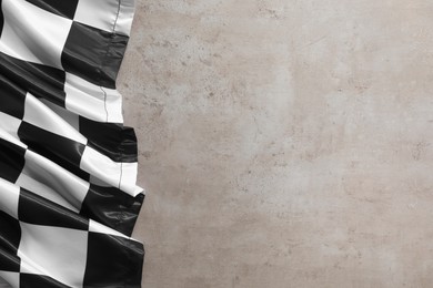 Photo of Checkered flag on grey table, top view. Space for text