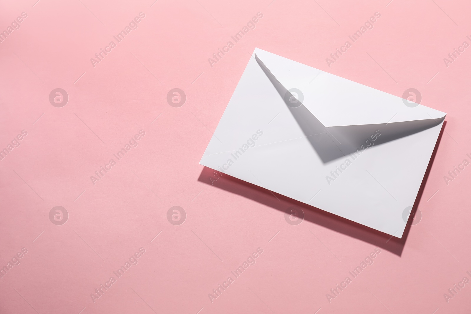 Photo of Paper envelope on pink background, top view. Mockup for design