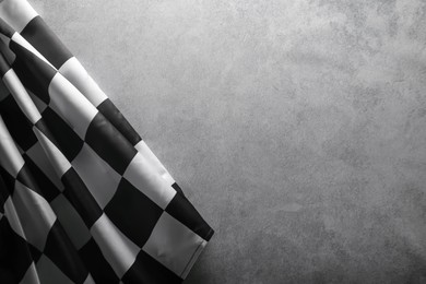 Photo of Checkered flag on grey table, top view. Space for text