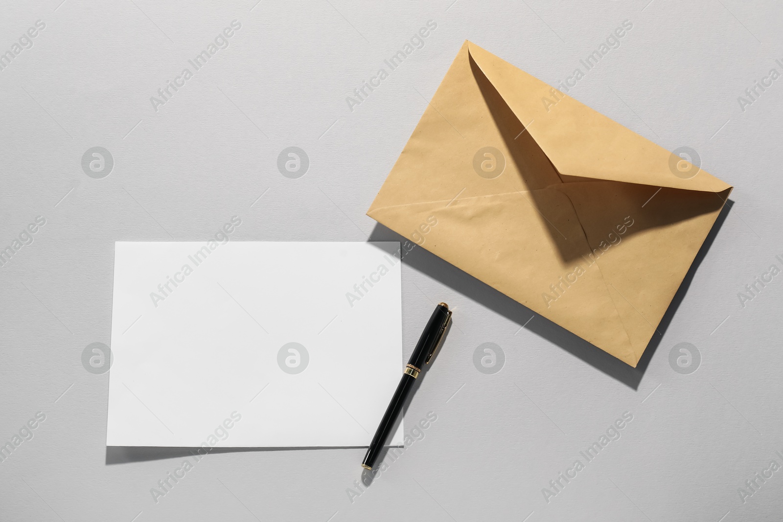 Photo of Kraft paper envelope, letter and pen on grey background, flat lay. Mockup for design