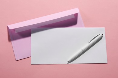 Paper envelopes and pen on pink background, top view. Mockup for design