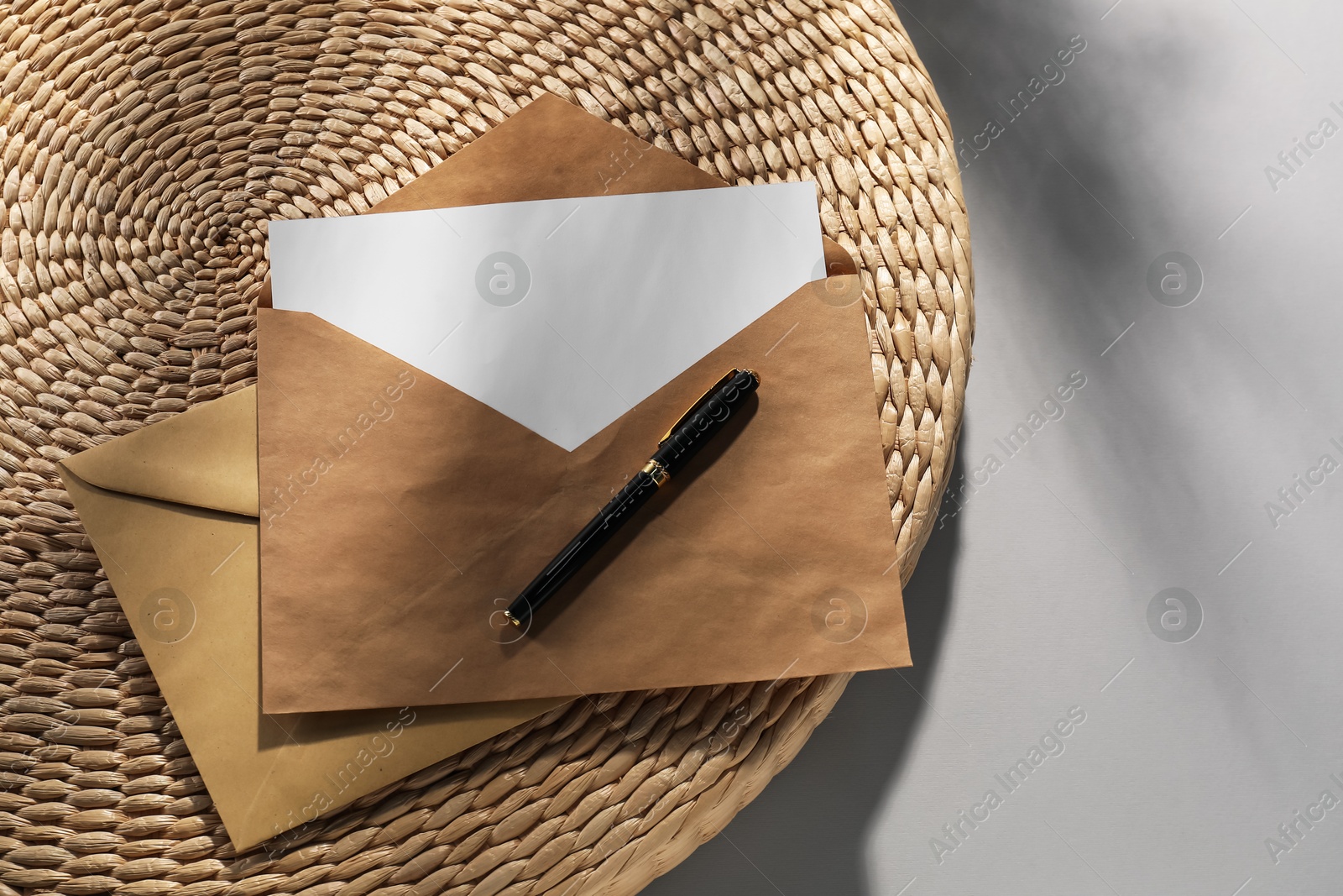 Photo of Kraft paper envelopes with letter and fountain pen on grey background, top view. Mockup for design