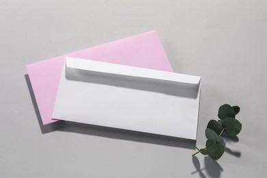 Paper envelopes and eucalyptus branch on grey background, top view. Mockup for design