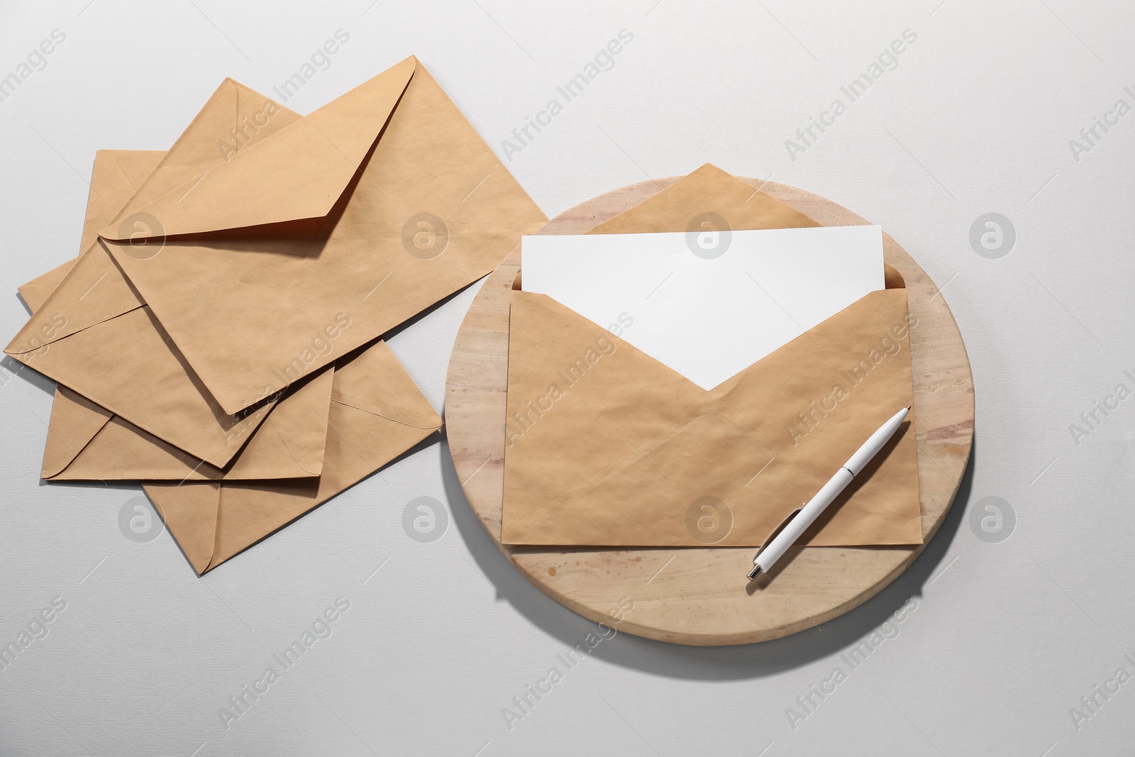 Photo of Kraft paper envelopes with letter and pen on grey background, flat lay. Mockup for design