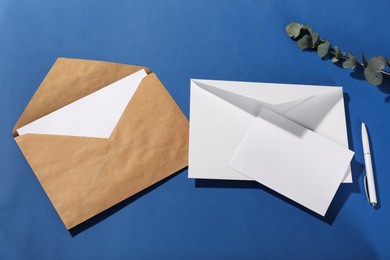 Photo of Paper envelopes with letters, eucalyptus branch and pen on blue background, flat lay. Mockup for design