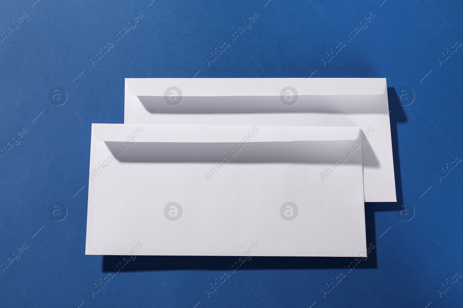 Photo of Paper envelopes on blue background, top view. Mockup for design