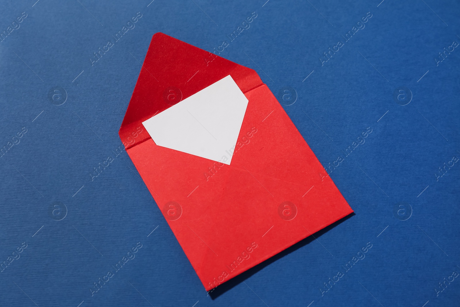 Photo of Paper envelope with letter on blue background, above view. Mockup for design