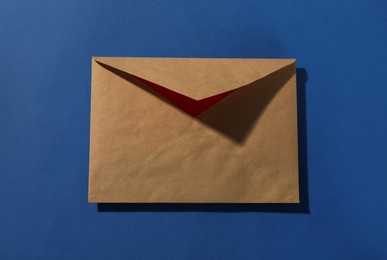 Kraft paper envelope on blue background, top view. Mockup for design