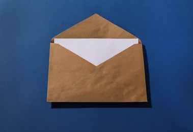 Photo of Kraft paper envelope with letter on blue background, above view. Mockup for design