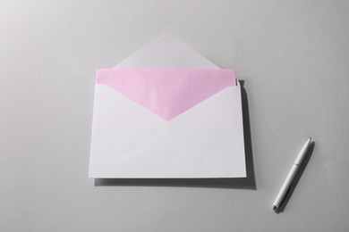 Photo of Paper envelope with letter and pen on grey background, above view. Mockup for design