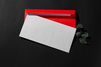 Paper envelopes and eucalyptus branch on black background, top view. Mockup for design