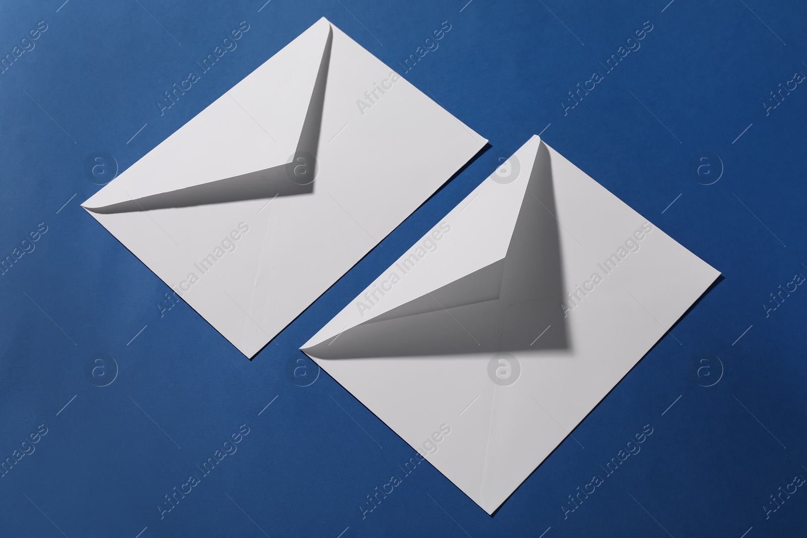 Photo of Paper envelopes on blue background, above view. Mockup for design