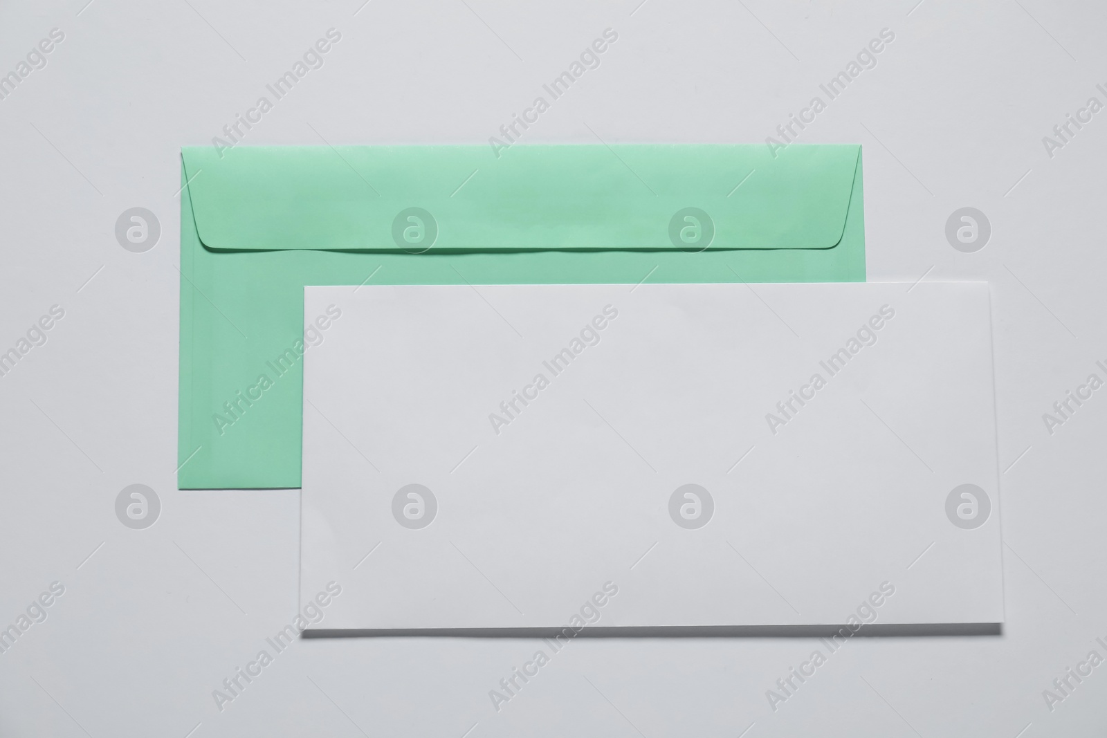 Photo of Paper envelope with letter on white background, top view. Mockup for design