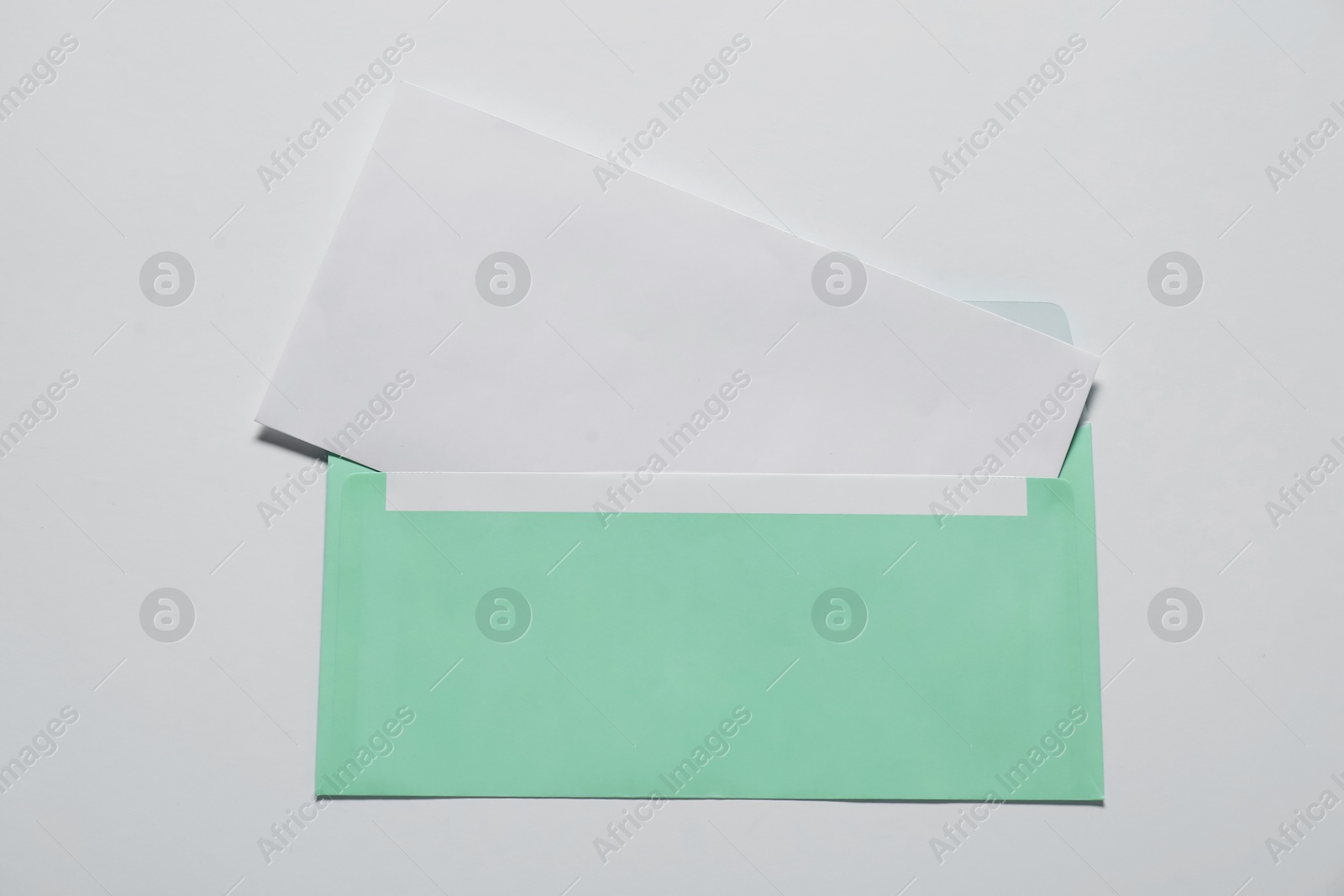 Photo of Paper envelope with letter on white background, top view. Mockup for design