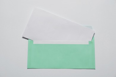 Paper envelope with letter on white background, top view. Mockup for design