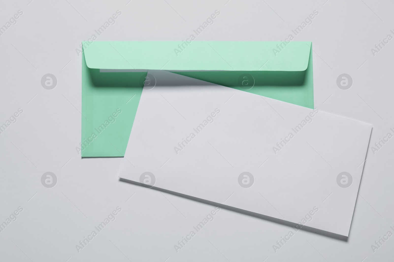 Photo of Paper envelope with letter on white background, top view. Mockup for design