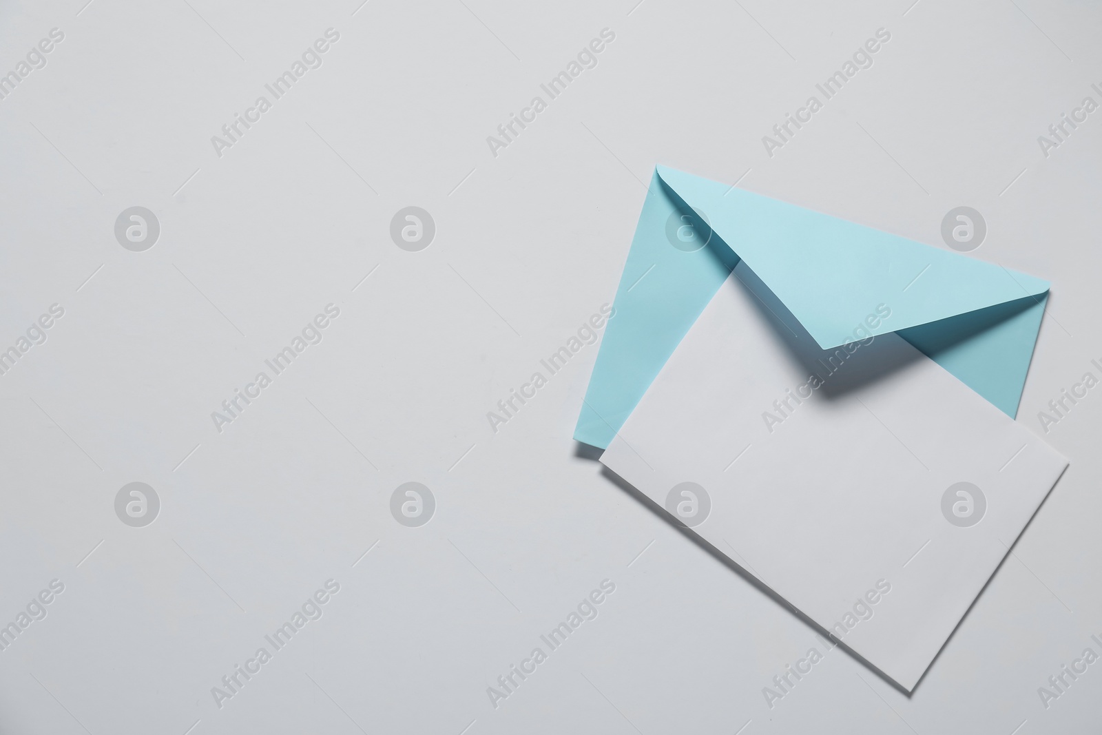 Photo of Paper envelope with letter on white background, top view. Mockup for design