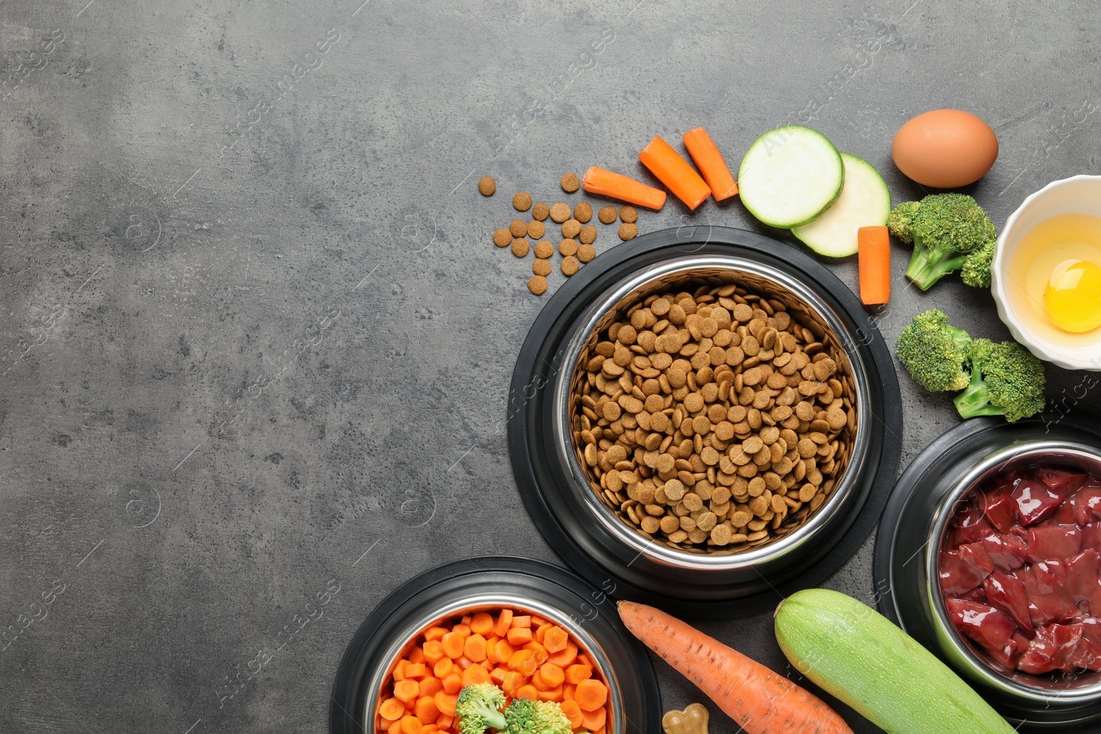 Photo of Dry pet food and natural products on grey table, top view. Space for text