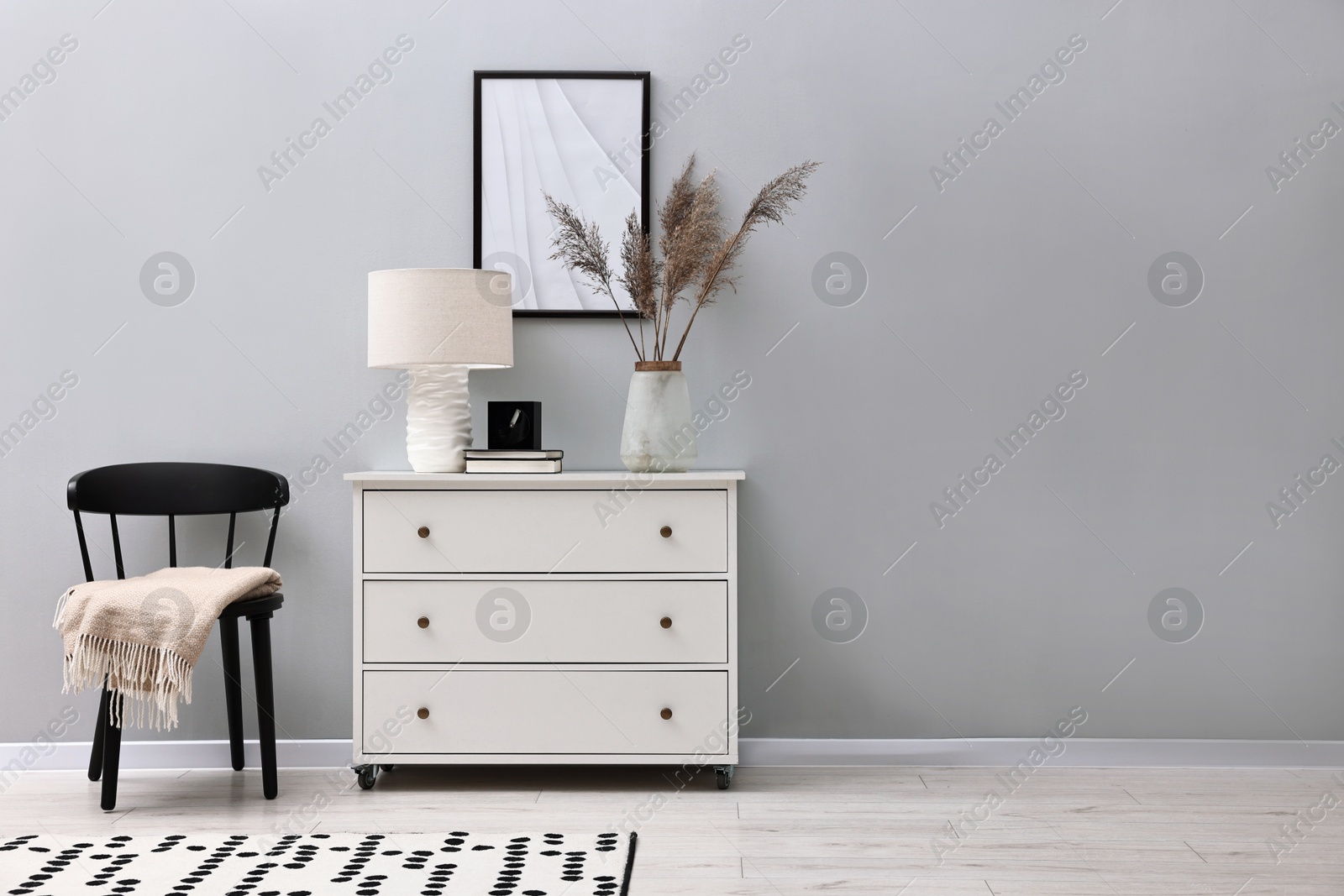 Photo of Dresser and chair near light grey wall in room, space for text. Interior design