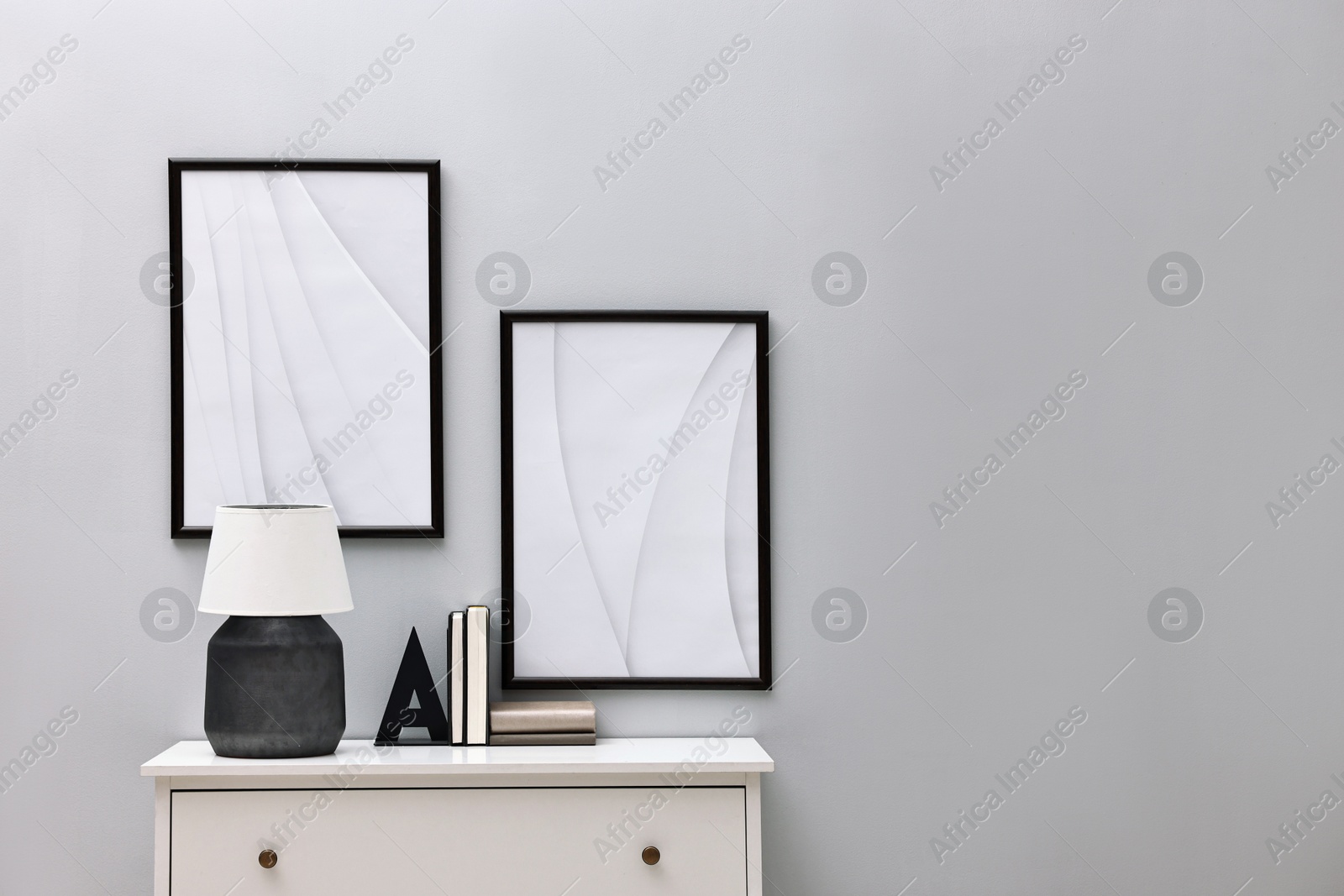 Photo of Console table with lamp and bookend near light grey wall, space for text. Interior design