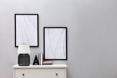 Photo of Console table with lamp and bookend near light grey wall, space for text. Interior design