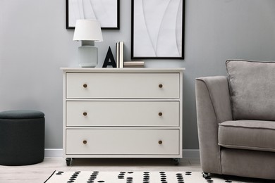 Photo of Dresser and other furniture near light grey wall in room. Interior design