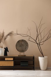 Photo of Console table and decor near dark beige wall in room. Interior design