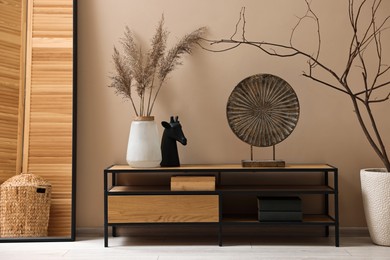 Photo of Console table and decor near dark beige wall in room. Interior design