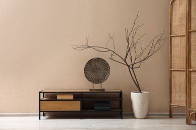 Photo of Console table and decor near dark beige wall in room. Interior design