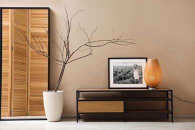 Photo of Console table with lamp and decor near dark beige wall in room. Interior design