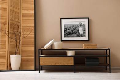 Photo of Console table and decor near dark beige wall in room. Interior design