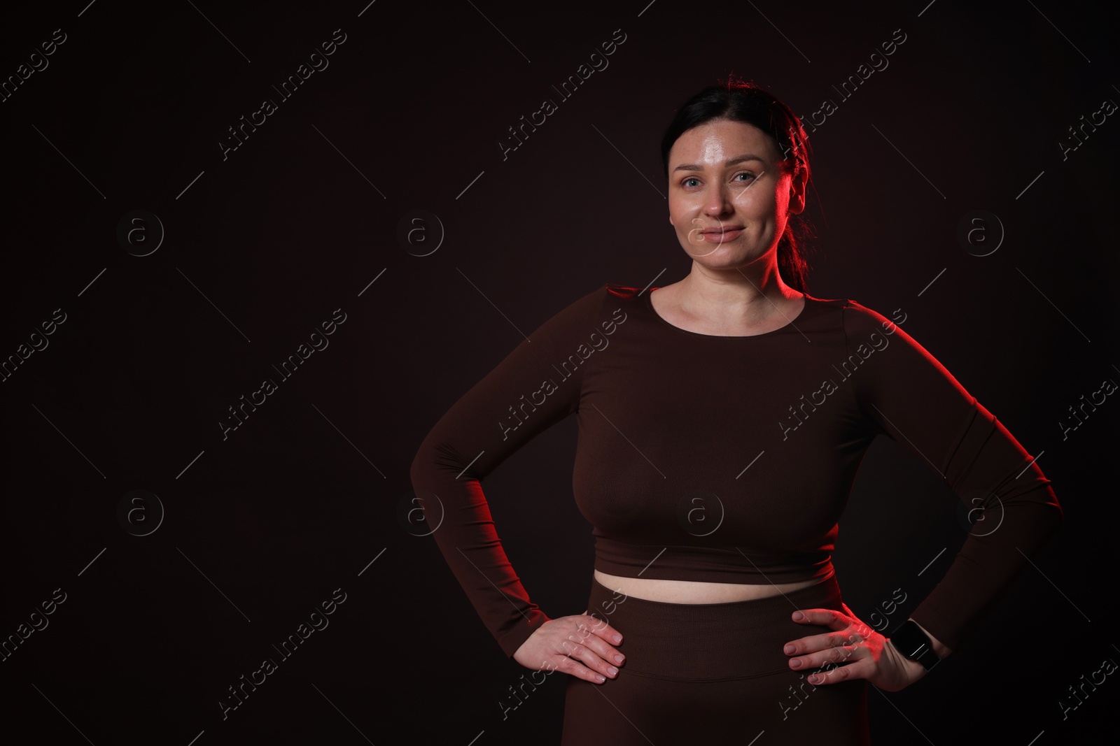 Photo of Plus size woman in gym clothes on black background, space for text