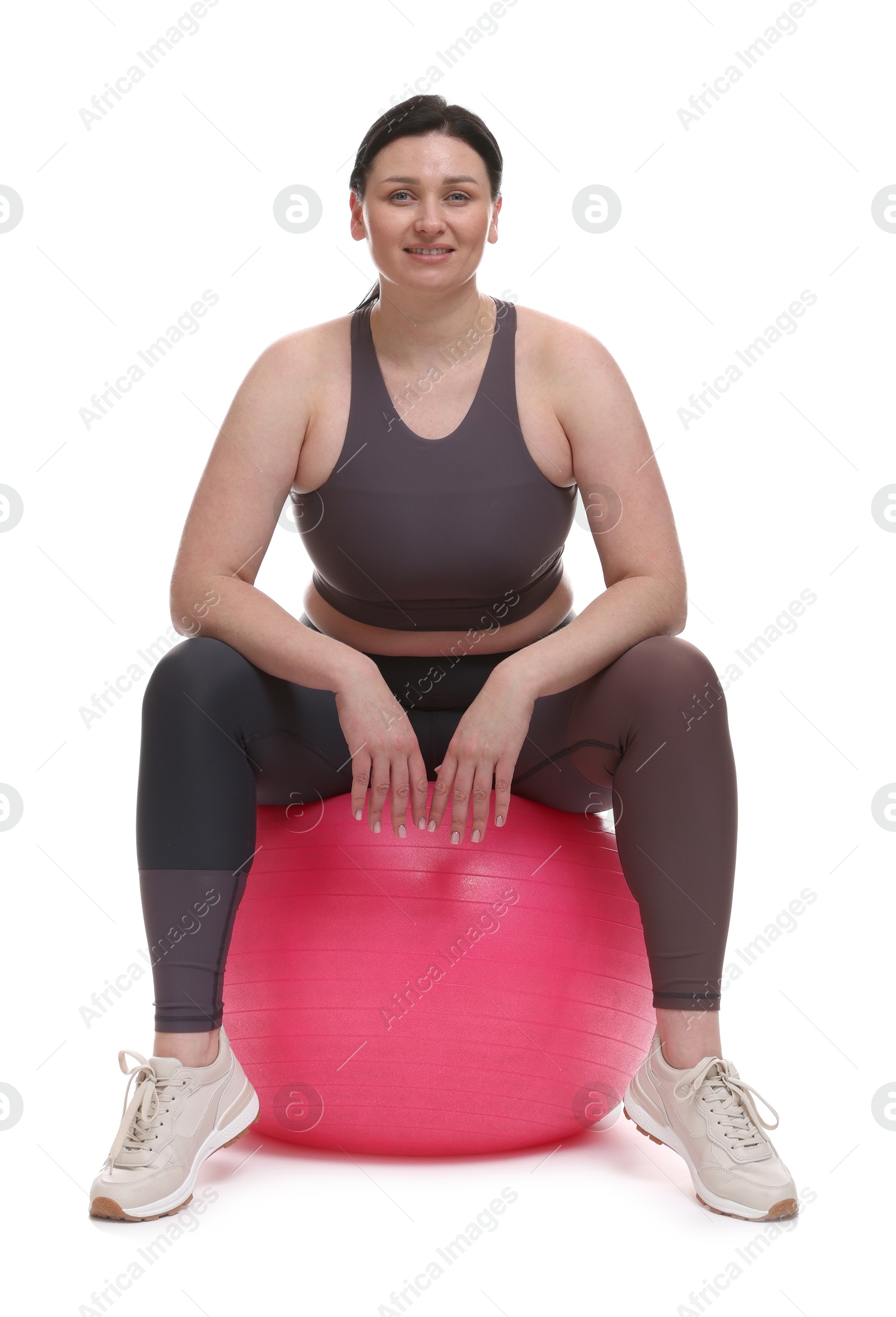 Photo of Plus size woman in gym clothes with fitness ball on white background