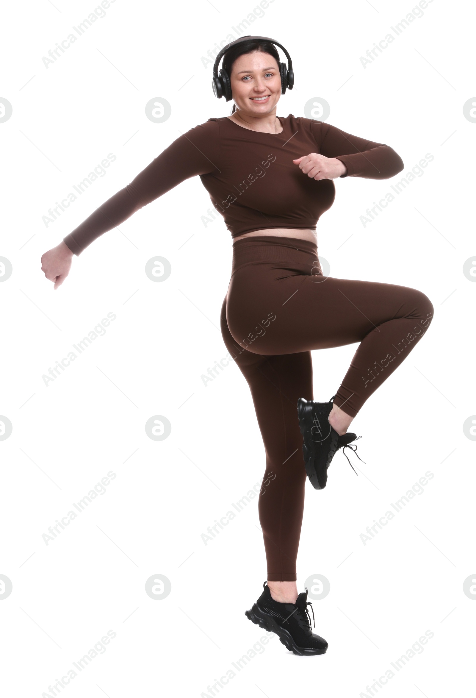 Photo of Plus size woman in gym clothes and headphones on white background