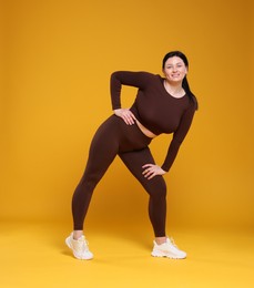 Photo of Plus size woman in gym clothes on orange background