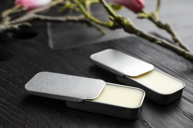 Photo of Natural solid perfume and branch on black wooden table, closeup