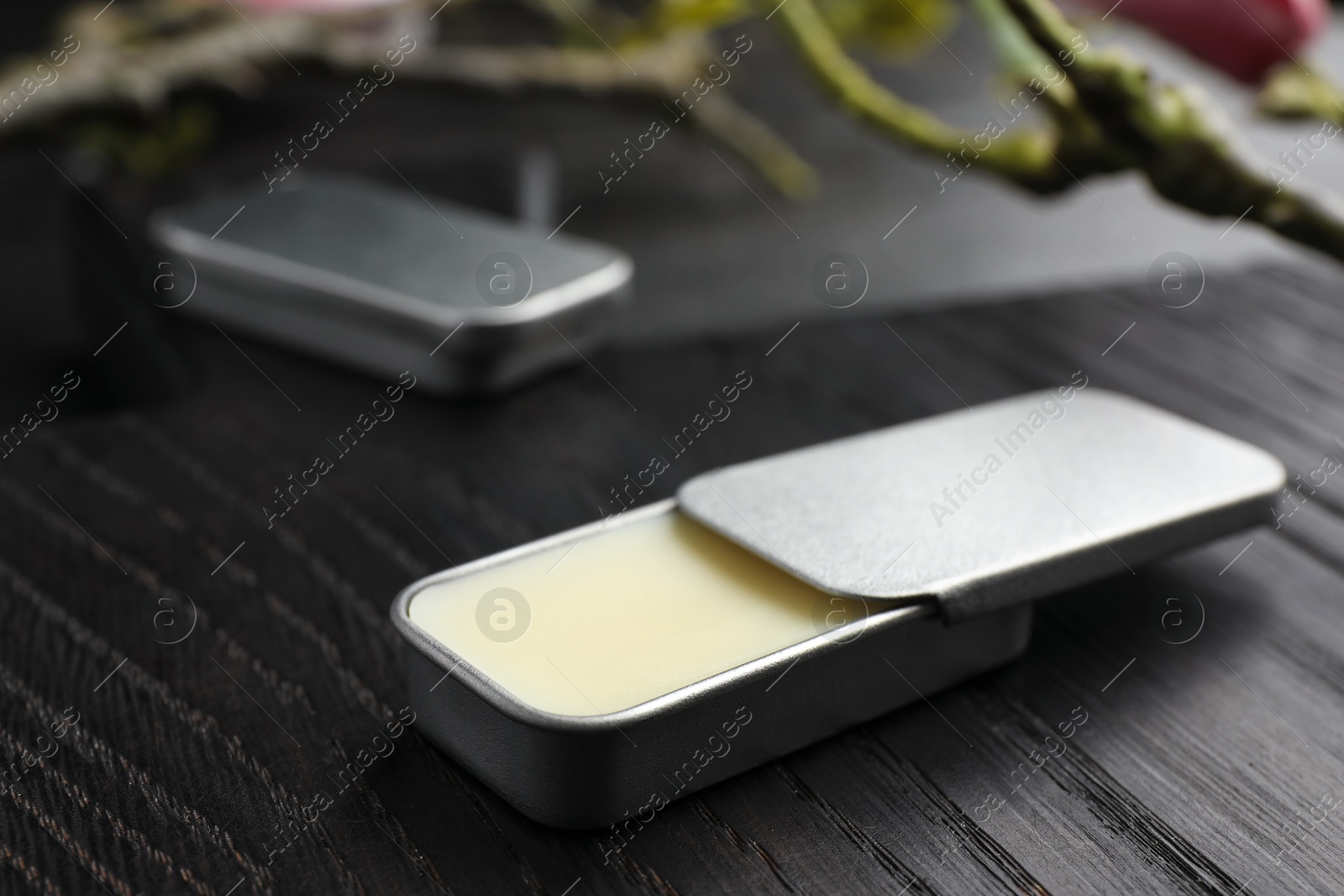 Photo of Natural solid perfume and branch on black wooden table, closeup