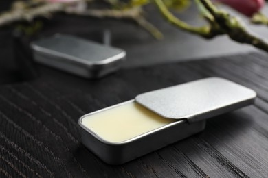 Photo of Natural solid perfume and branch on black wooden table, closeup