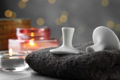 Photo of Spa stones, towel and burning candles on grey table, closeup