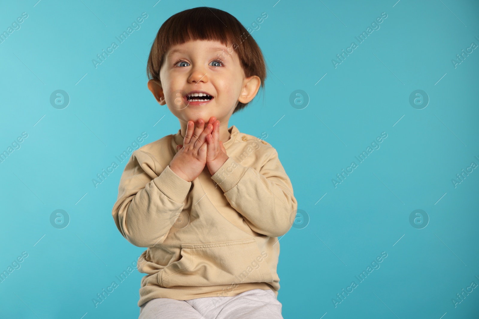 Photo of Portrait of happy little boy on light blue background. Space for text