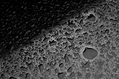 Photo of Water drops on dark grey glass surface, closeup