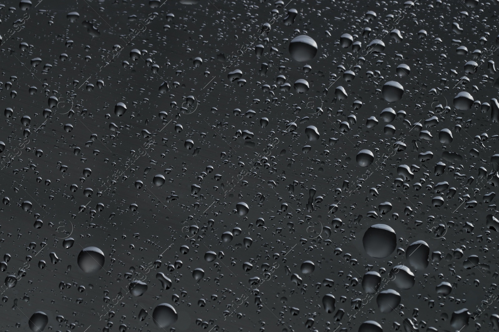 Photo of Water drops on dark grey glass surface, top view