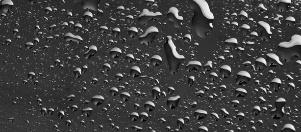 Photo of Water drops on grey glass surface, top view