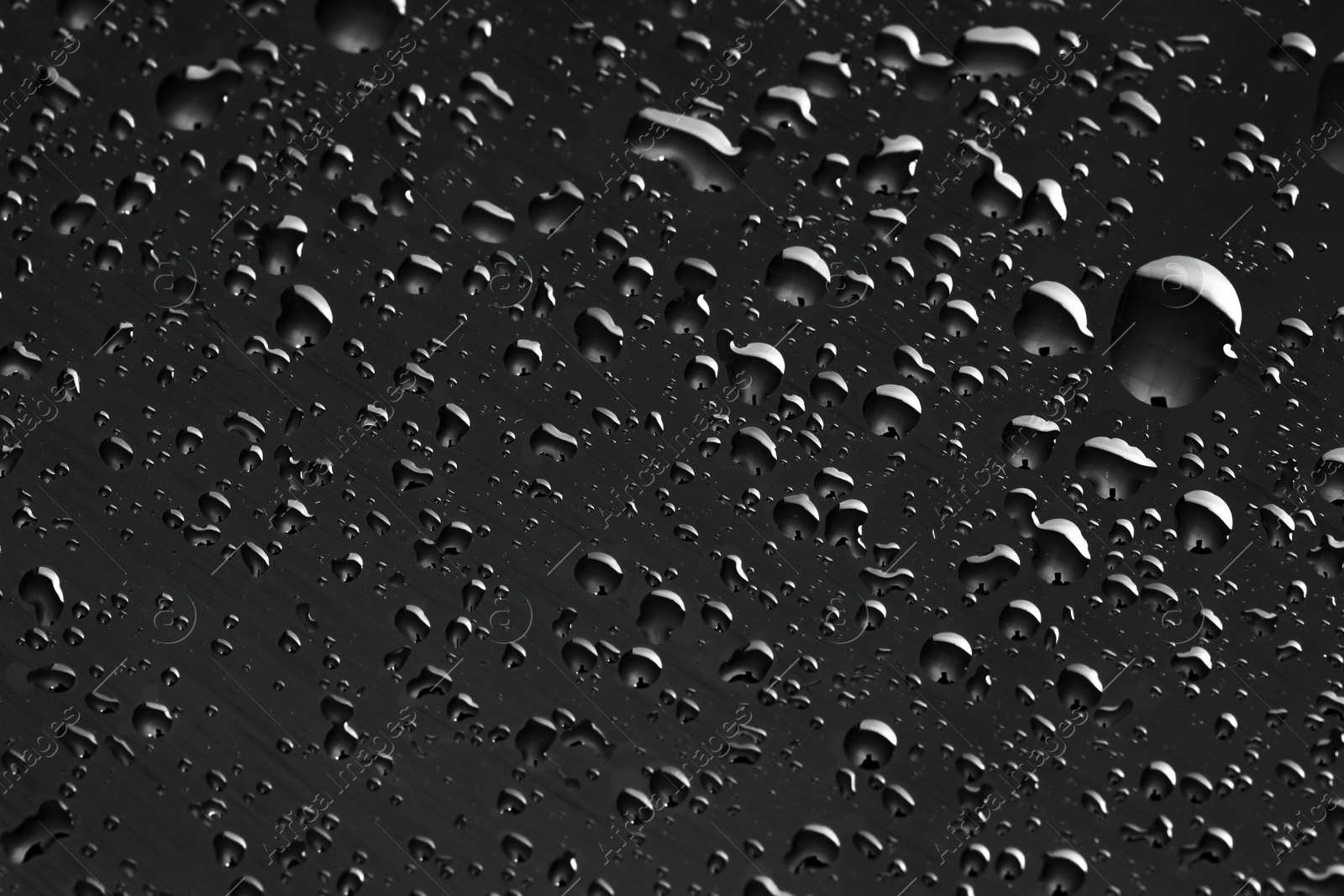 Photo of Water drops on dark grey glass surface, top view