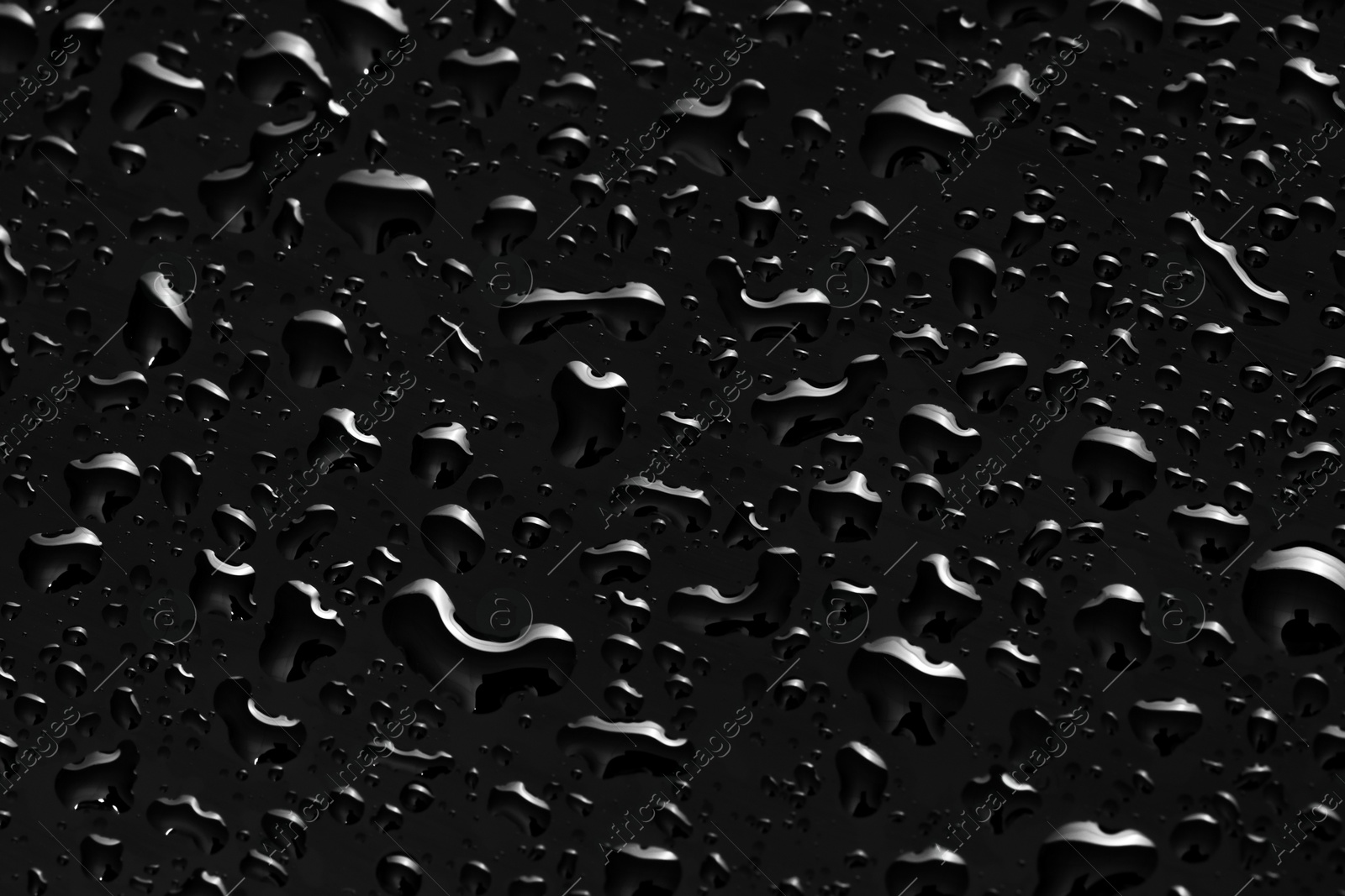 Photo of Water drops on black glass surface, closeup