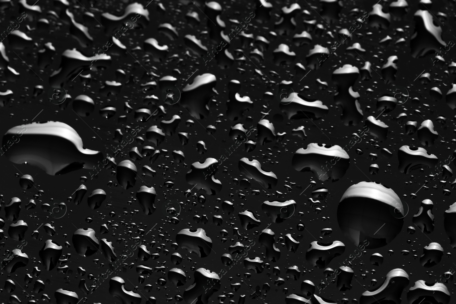 Photo of Water drops on black glass surface, closeup