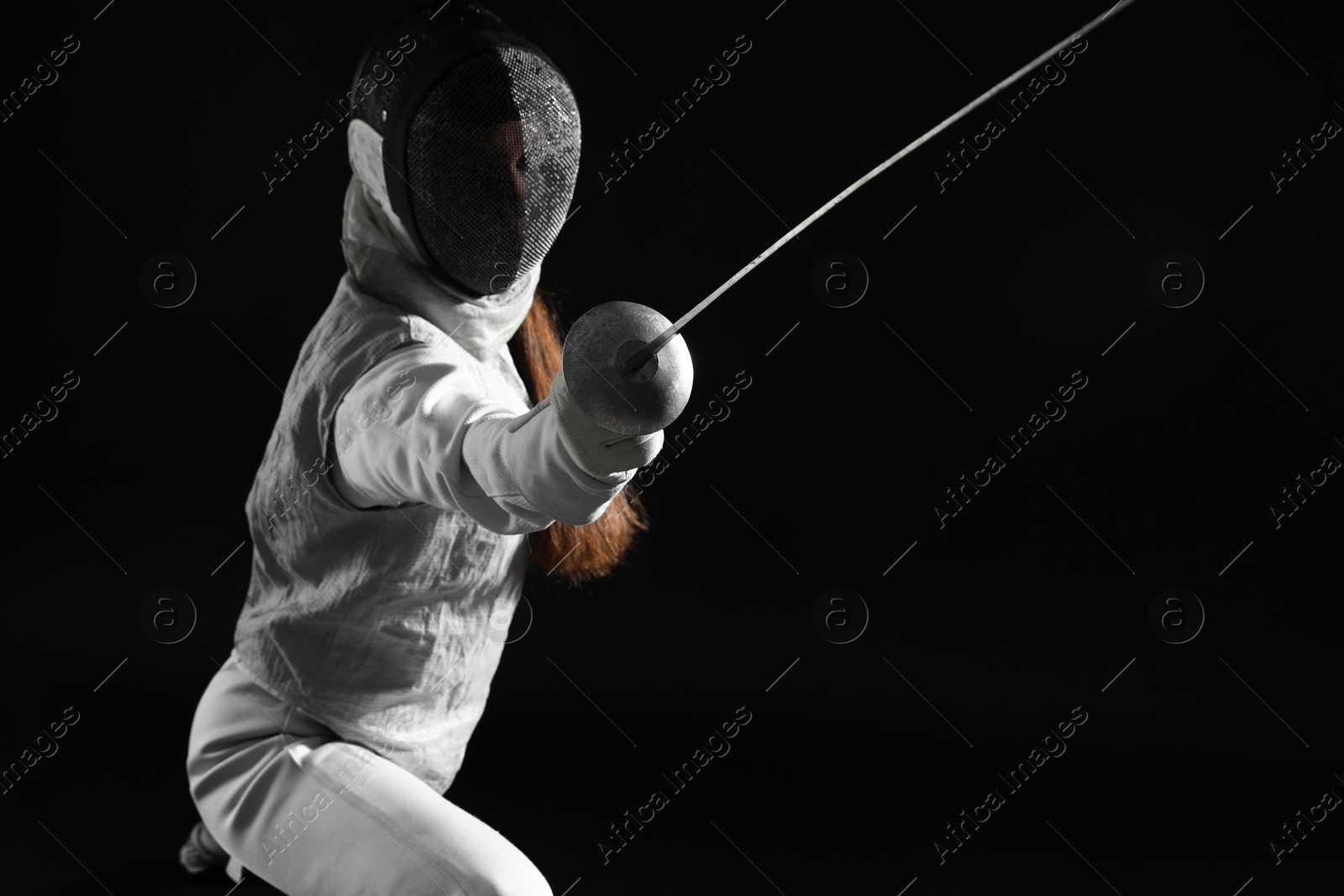 Photo of Fencer with epee practicing on black background