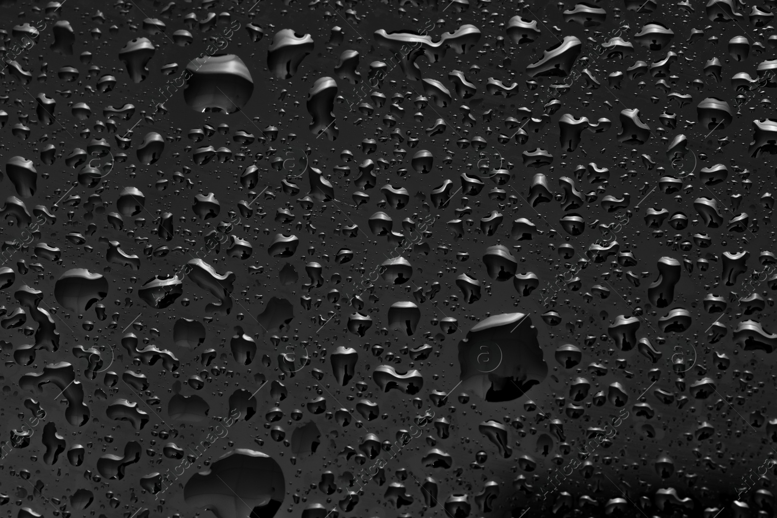 Photo of Water drops on dark grey glass surface, top view