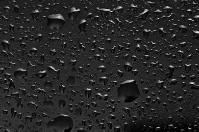 Water drops on dark grey glass surface, top view